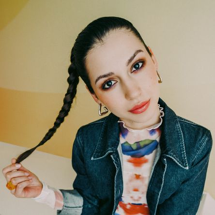 Mladá žena s copy v džínové bundě vyzařuje energii a autenticitu. Fotka ke kampani Práce mění život