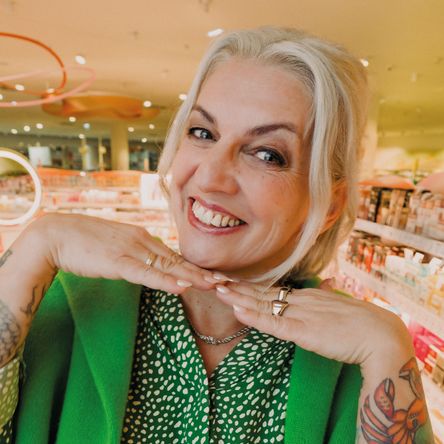 ena v módním zeleném outfitu se usmívá v příjemném prostředí prodejny dm. Fotka ke kampani Práce mění život