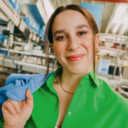 Mladá žena v zelené košili  s milým úsměvem. Fotka ke kampani Práce mění život