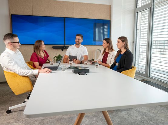 Spolupracovníci sedí v jednací místnosti a diskutují na určité téma.