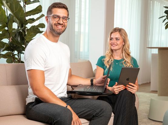 Muž a žena sedí v křeslech na recepci a usmívají se.