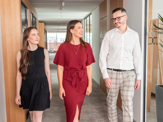 Tři spolupracovníci procházejí chodbou dialogica.