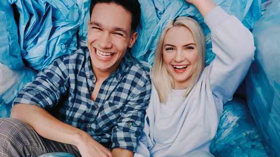 Mladý muž a žena se smějí ve uvolněném prostředí, což ilustruje přátelskou atmosféru a týmového ducha v dm.. Fotka ke kampani Práce mění život