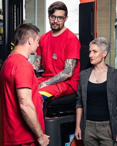 Tři spolupracovníci logistického centra diskutují u vozíku.