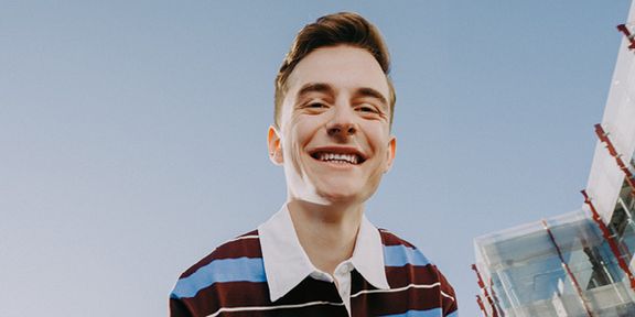 Mladý muž smějící se do kamery za krásného slunečného počasí. Fotka ke kampani Práce mění život