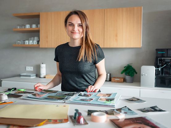 Spolupracovnice dm zachycena ve svém domově, jak ve volném čase vkládá fotky do alba.